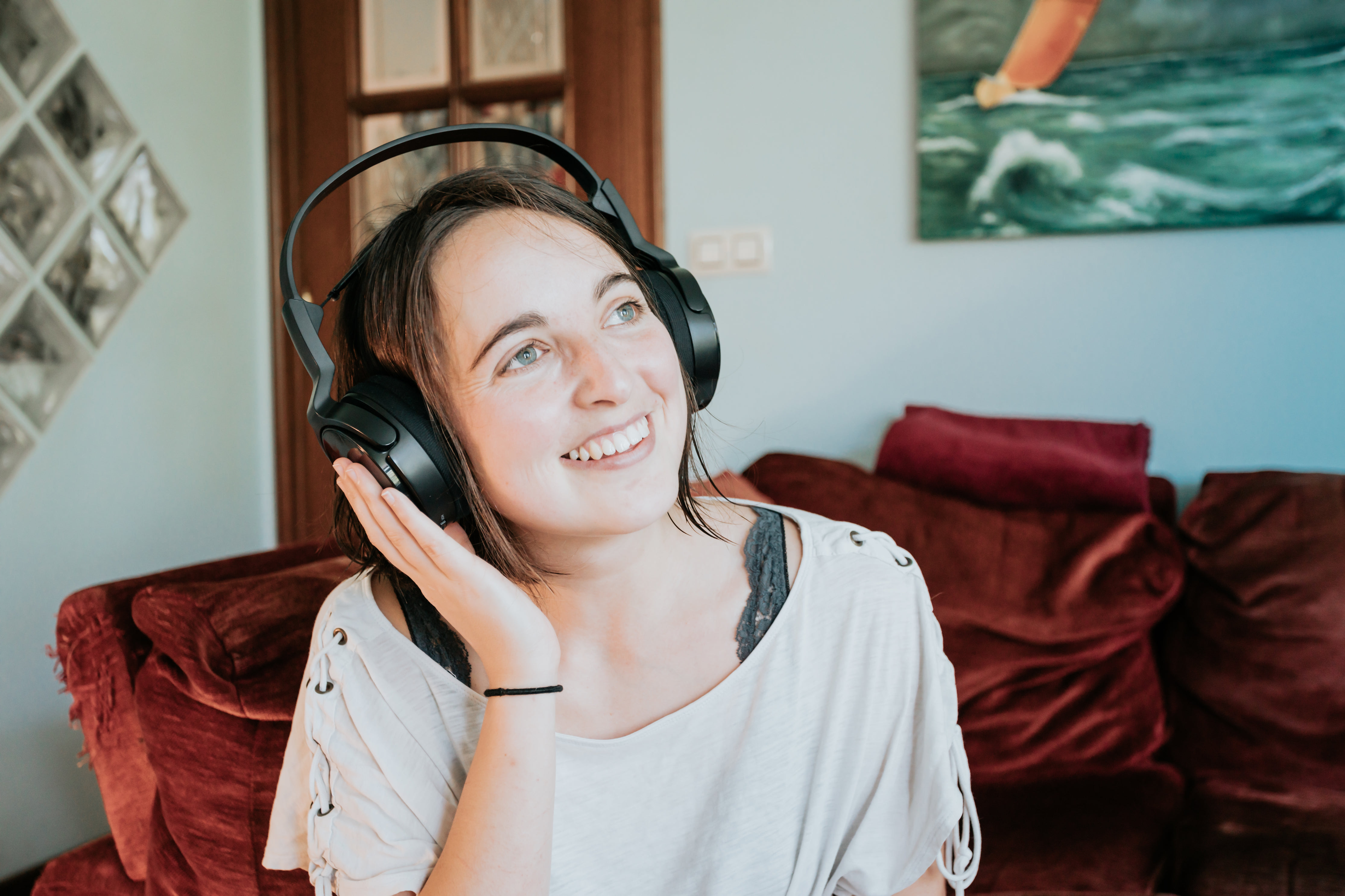 woman-wears-headphones-with-one-hand-up-smiling.jpg